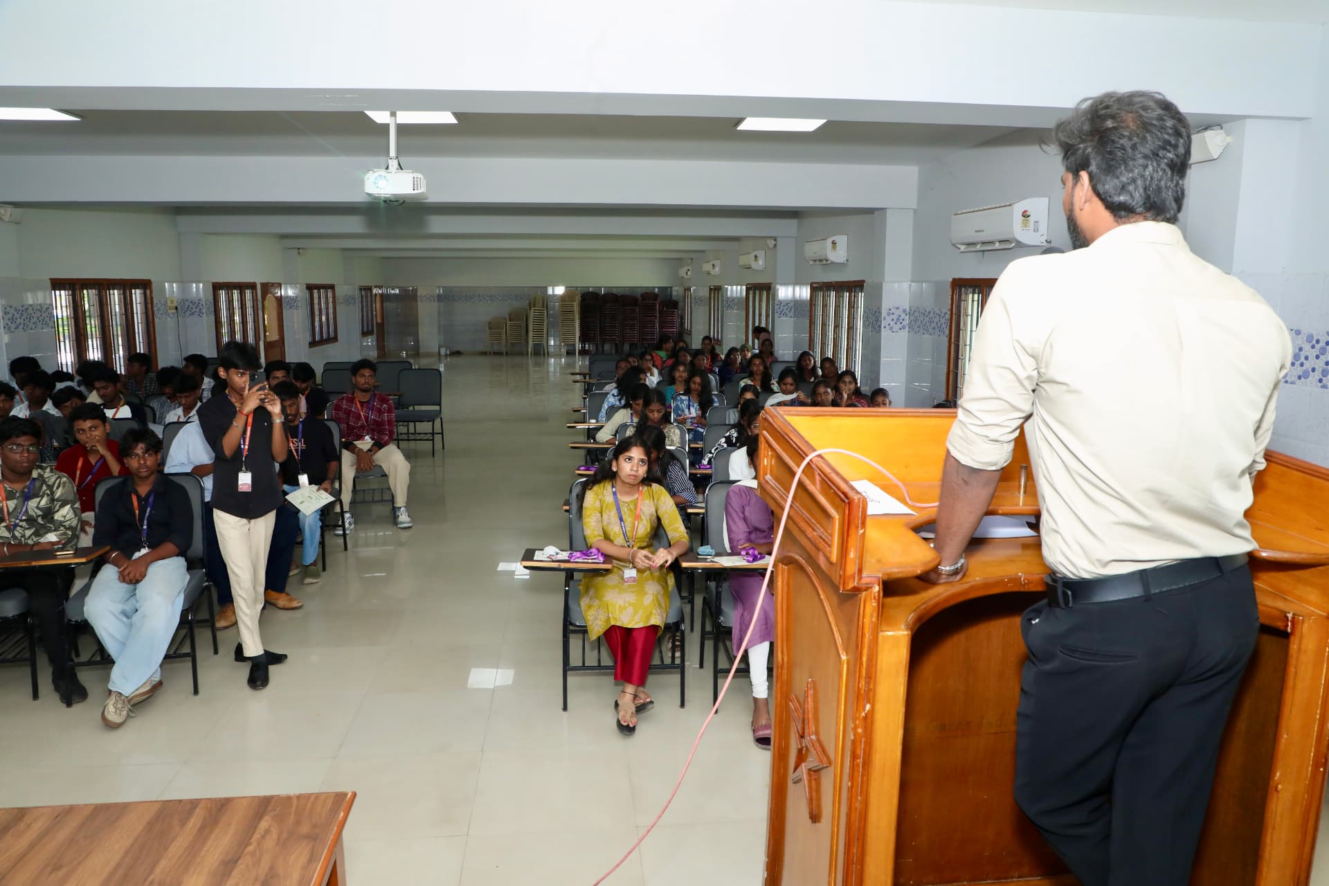 A B2E speaker addressing students from the college auditorium stage